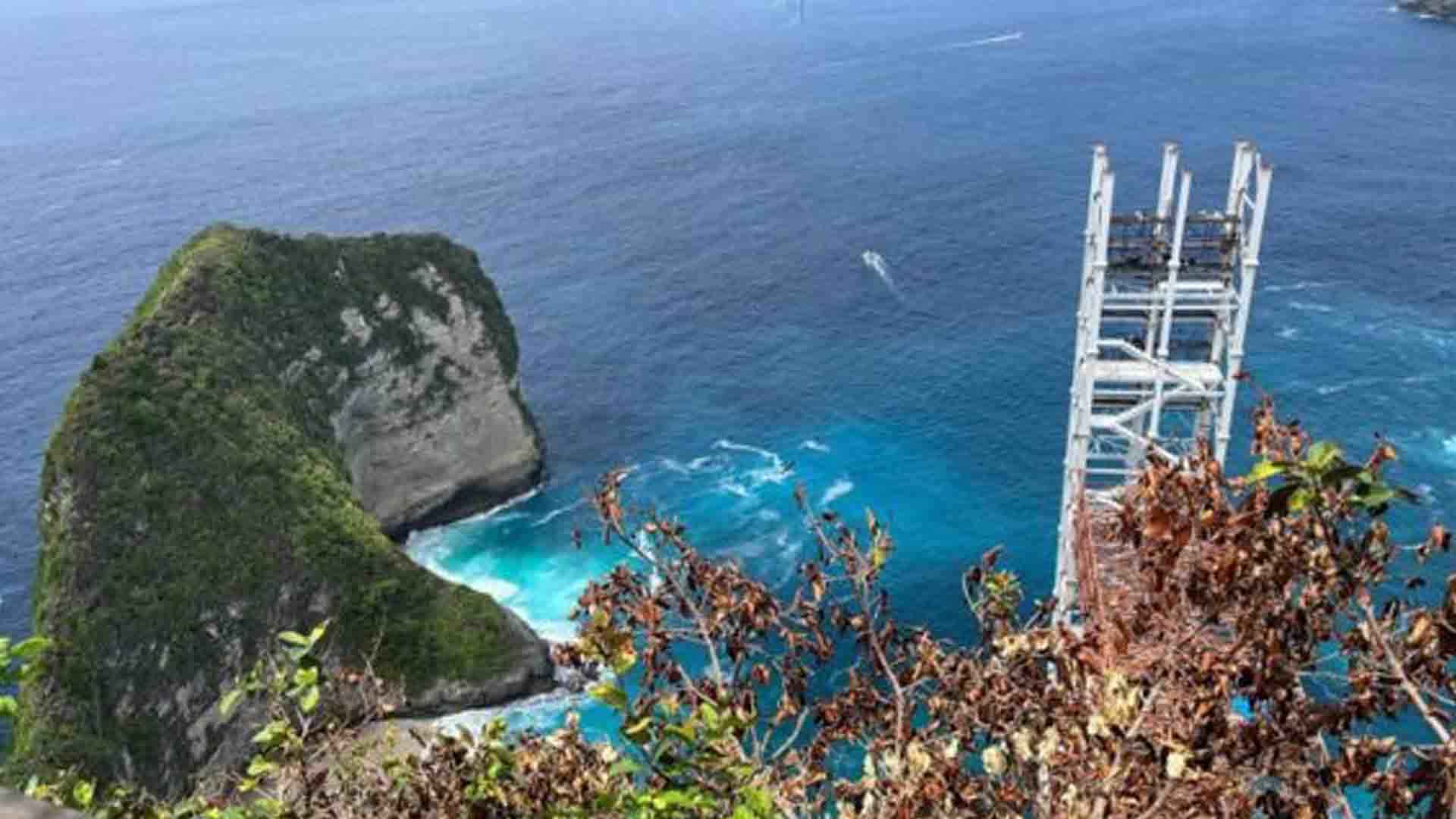 Panorama Pantai Kelingking di Nusa Penida, Bali, terlihat dari atas tebing dengan laut biru jernih dan pasir putih.